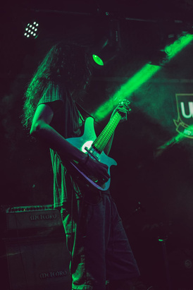 Daniel Curi tocando baixo sob luz verde